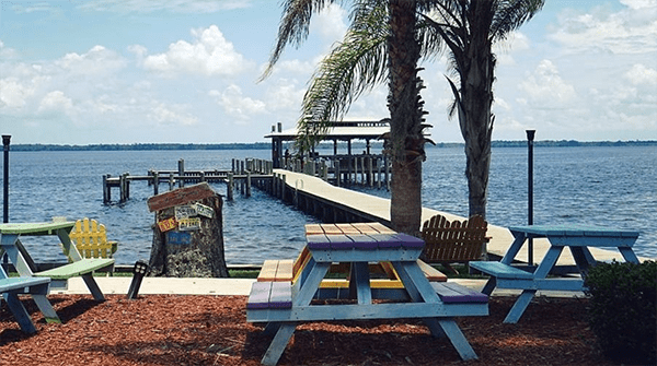 A view of a pier and picnic tables in front of a ocean